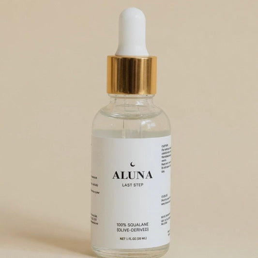 Bottle of Aluna serum with dropper on a beige background